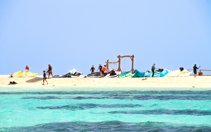 Kitesurfers preparing their gear on a remote sandbank, surrounded by turquoise water near Somabay.