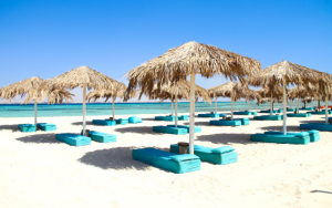 Sandy beach on Tobia Island with cosy sun loungers and parasols in front of turquoise blue water