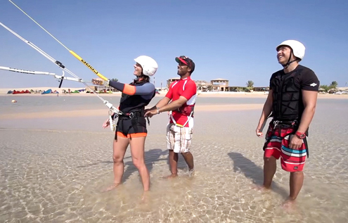 A professional kitesurfing instructor guiding two students through their first kite control exercises in shallow water at Kitehouse Somabay. Ideal conditions for safe and effective learning.