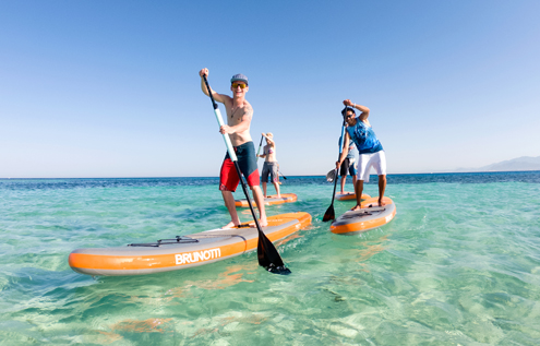 Four people enjoying stand-up paddling on crystal-clear water at KiteHouse Somabay