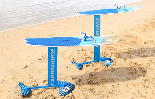Two blue Cabrinha hydrofoil boards standing on the sandy beach near the water at KiteHouse Somabay