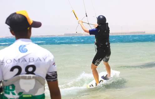 A kitesurfing student making their first successful water start while an instructor observes closely at Kitehouse Somabay. Perfect learning conditions with warm water and steady winds.