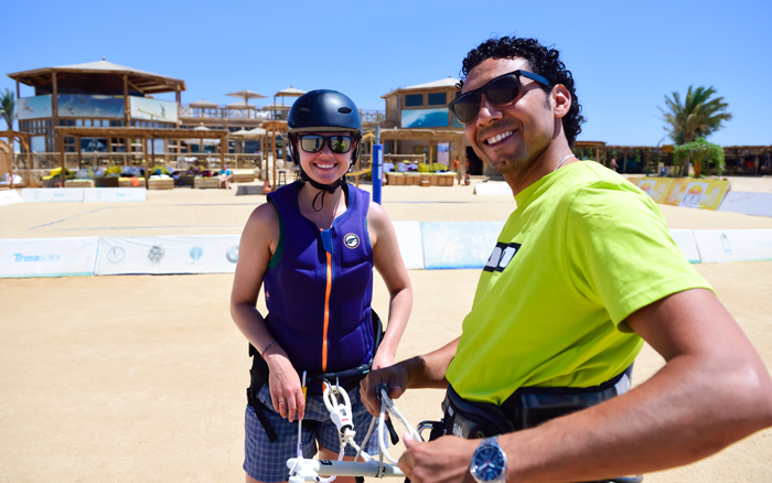 A beginner kitesurfing student in protective gear receiving hands-on training from a professional instructor at Kitehouse Somabay. The sunny weather and modern facilities create the perfect learning environment.
