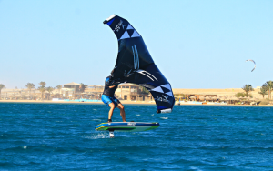 A wingfoiler on the sea and the 7BFT Kitehouse in the background