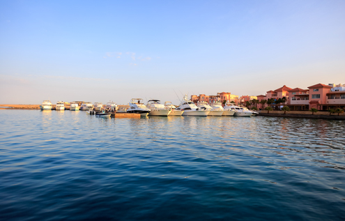 Luxury yachts in the marina of Somabay, surrounded by elegant villas and illuminated by the golden light of the sunset.