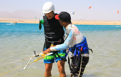 A kitesurfing student receives hands-on instruction from an experienced instructor in a shallow lagoon—perfect conditions for safe and effective learning.