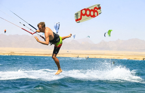 A kitesurfer mid-air after losing his kiteboard at Kitehouse Somabay, with the Red Sea and mountains in the background.
