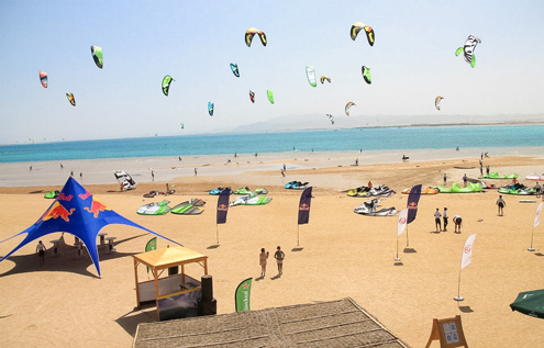 Blick auf den Strand des 7 Bft KiteHouse in Somabay während der Kitesurf-Weltmeisterschaft – mit unzähligen Kites am Himmel und einer lebhaften Atmosphäre.